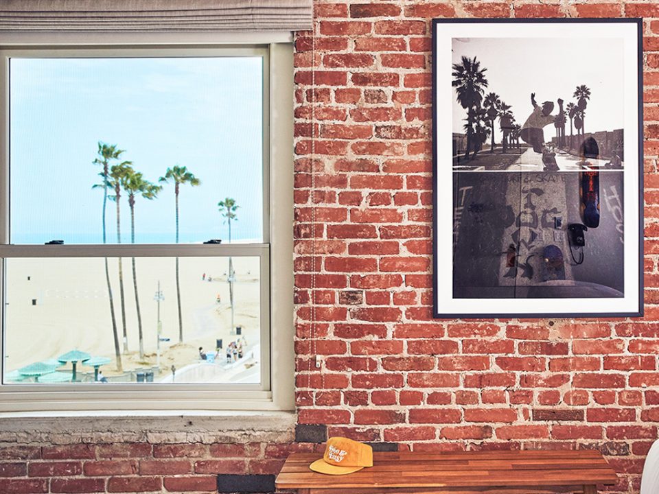 Detail shot inside bungalow of brick wall with picture frame and window view of venice boardwalk