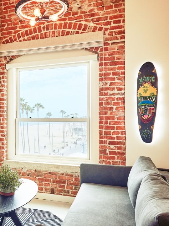 seating area with couch and skateboard wall decor, along with a view of venice boardwalk