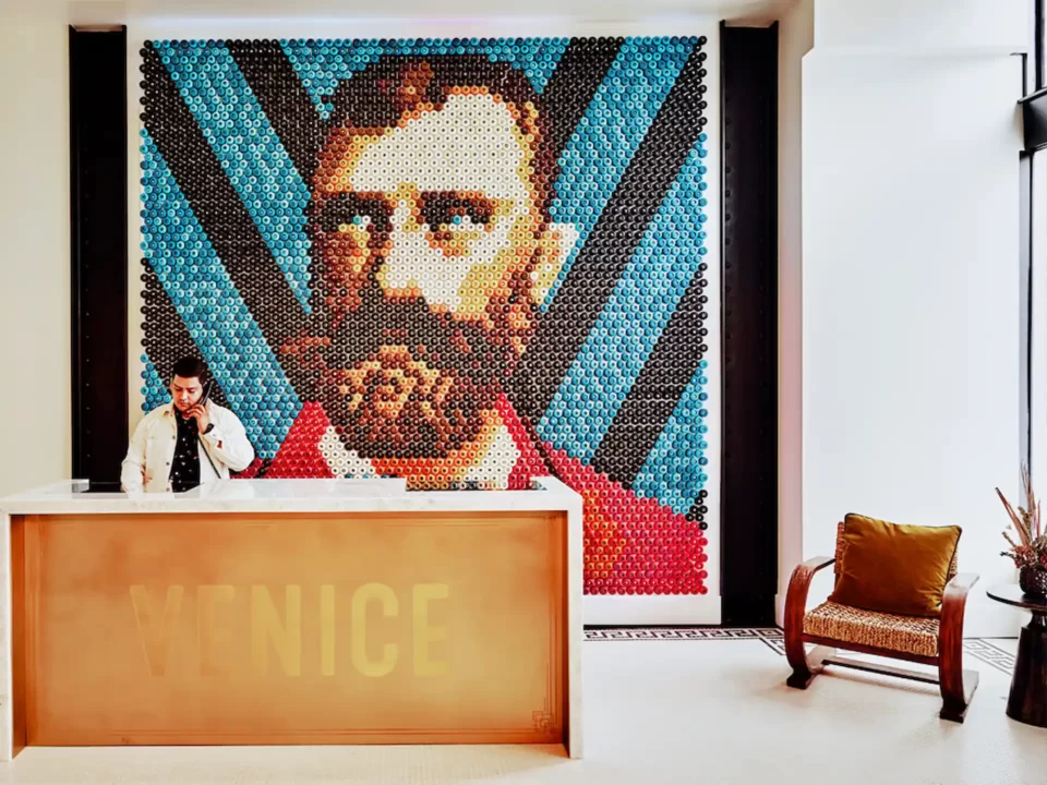 Venice V Reception desk with front desk agent on phone in front of wall mural.